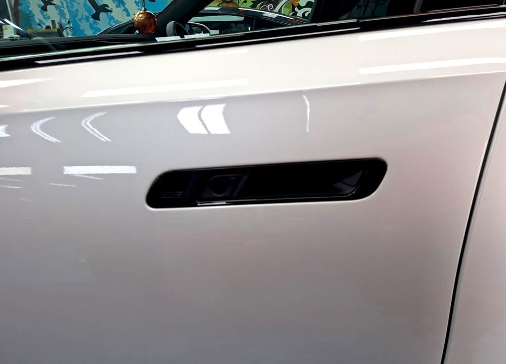 Flush black door handle set into the white door panel of the i7.