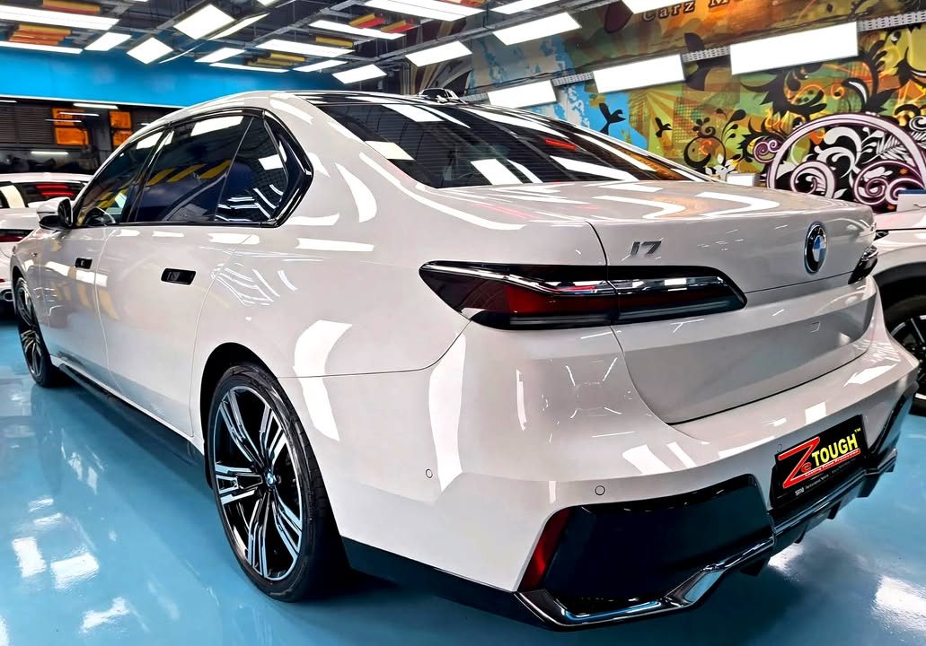 Rear three-quarter view of the white BMW i7 showing the tail lights and i7 badge.