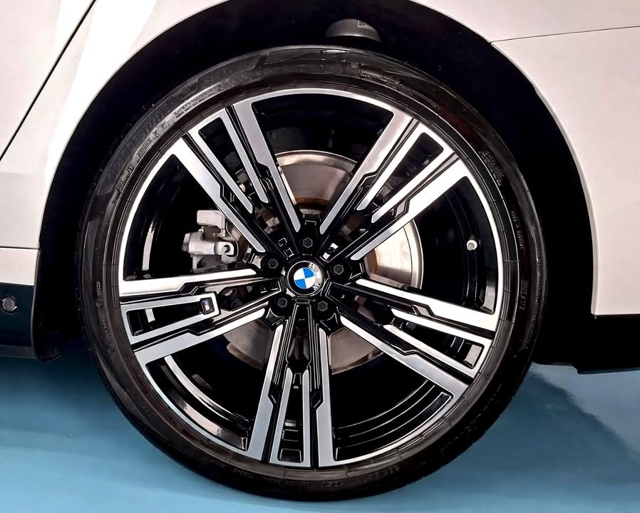 Two-tone multi-spoke wheel on the white BMW i7, with the brake disc visible.