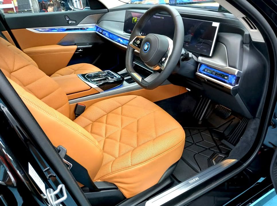 Front cabin of the BMW i7 with quilted cognac leather seats and curved display.