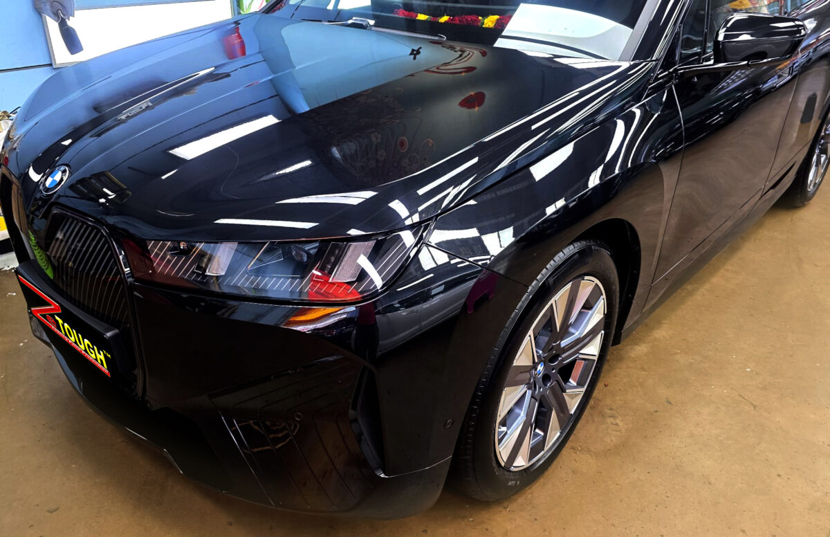 The BMW iX's coated paintwork under workshop lighting.