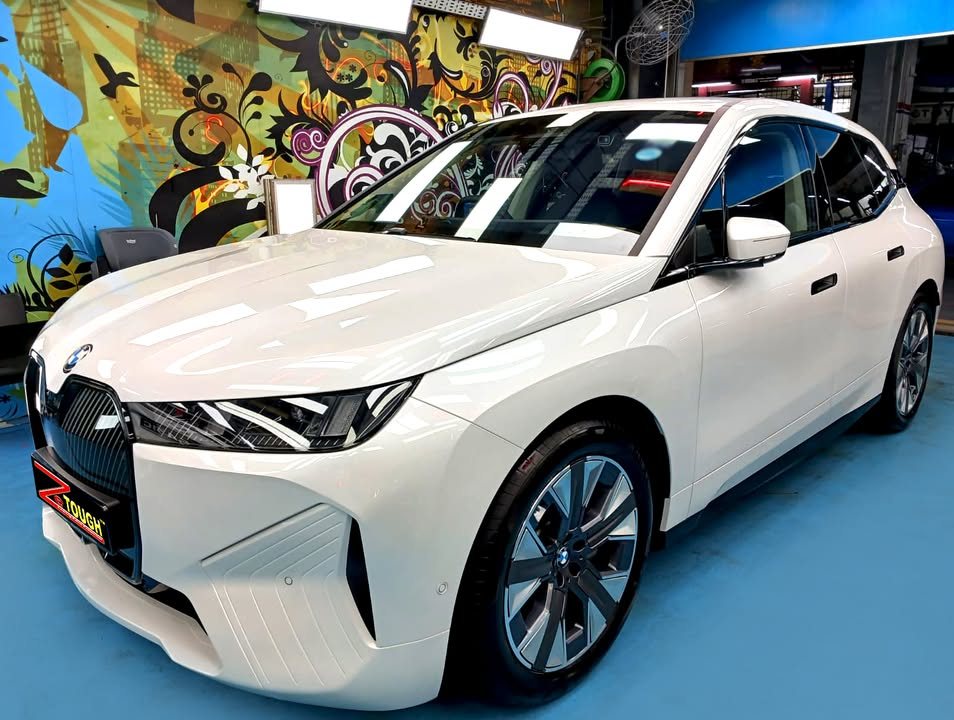 White BMW iX, front three-quarter view, in the Revol Carz Makeover workshop after its ZeTough Titanium coating.