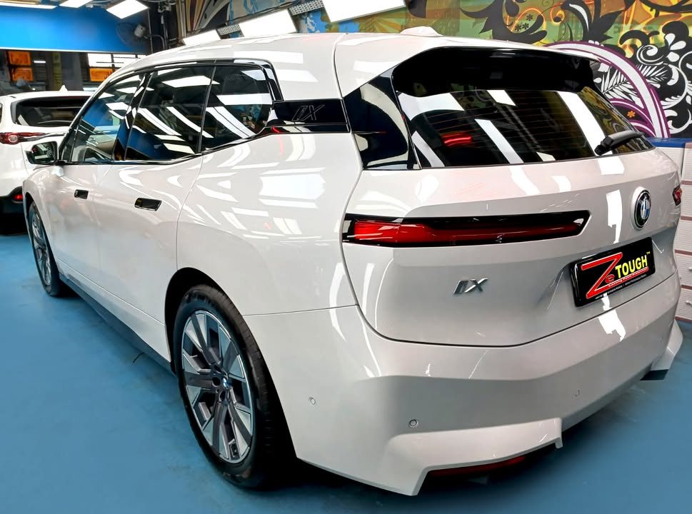 Rear three-quarter view of the white BMW iX with its slim rear lights.