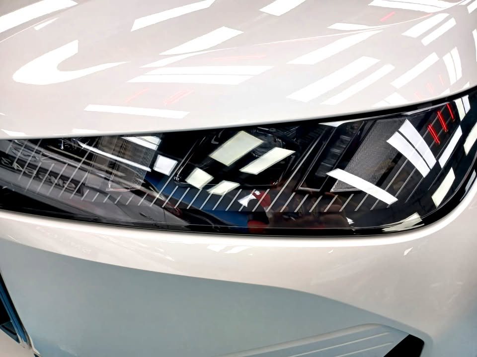 Close-up of the iX headlamp beside the white front bumper.