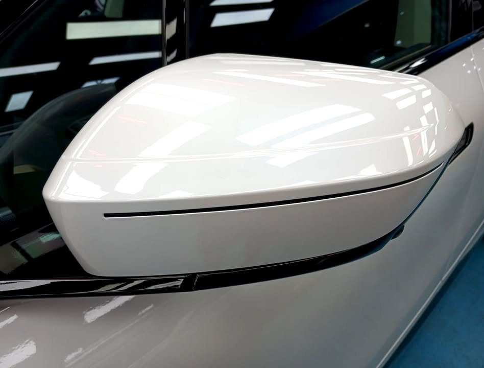 White side mirror cap reflecting the workshop lights.