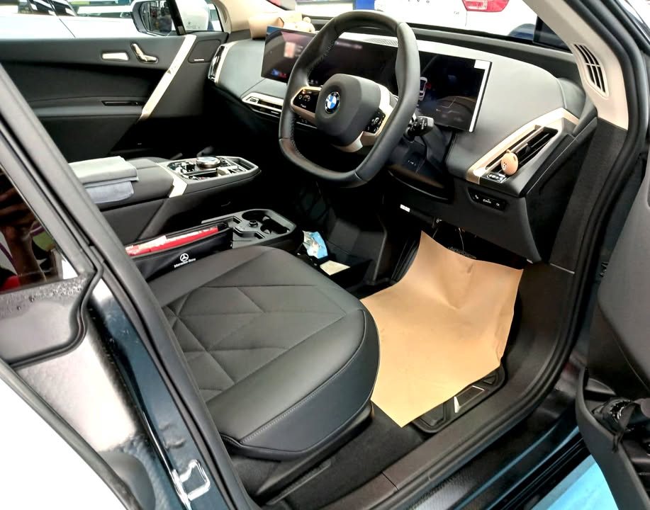 BMW iX interior with dark seats, steering wheel and curved display.