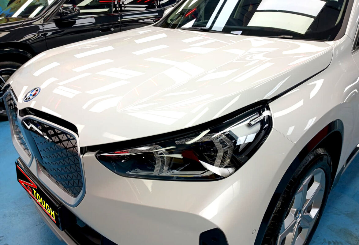 The BMW iX1's coated paintwork under workshop lighting.