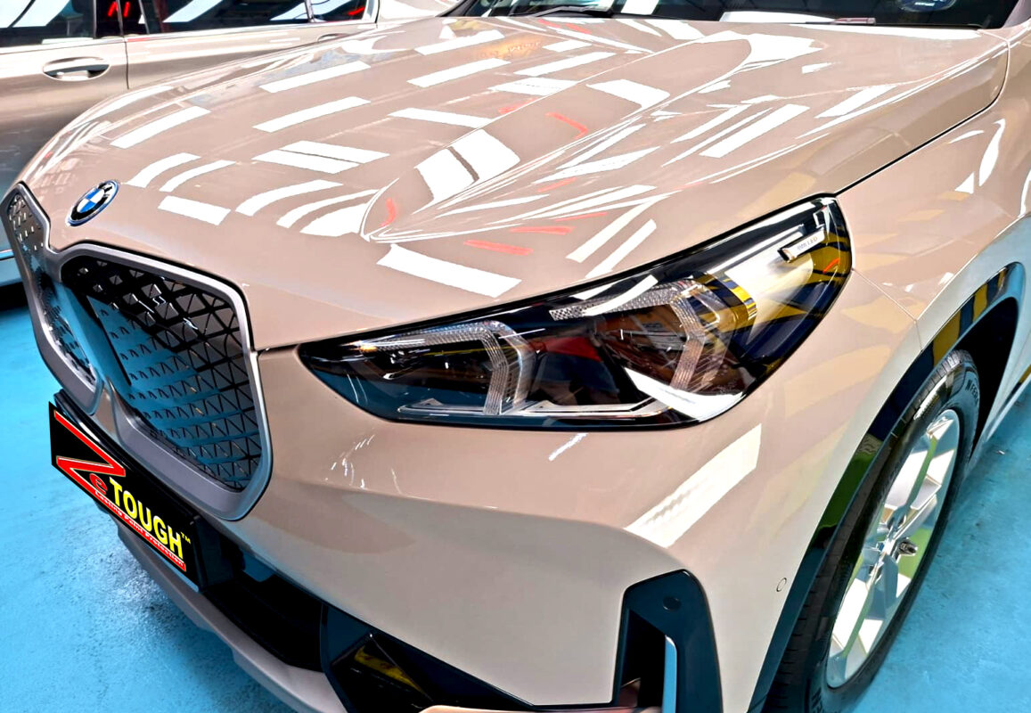 The BMW iX1's coated paintwork under workshop lighting.