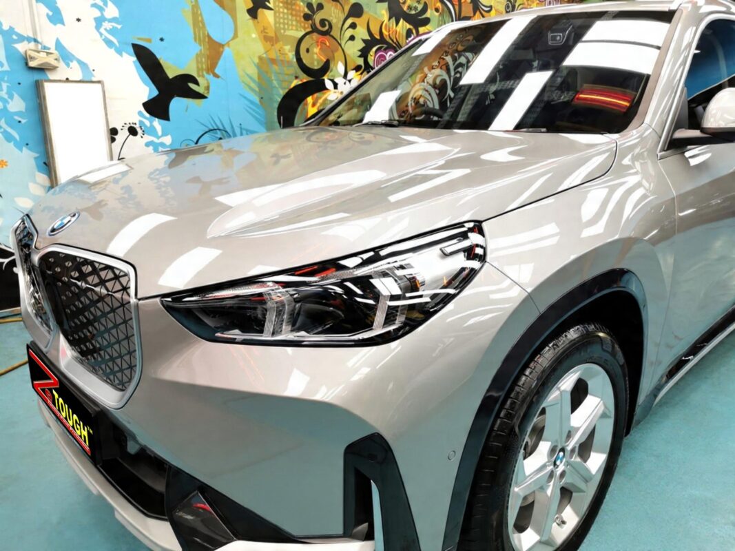 The BMW iX1's coated paintwork under workshop lighting.