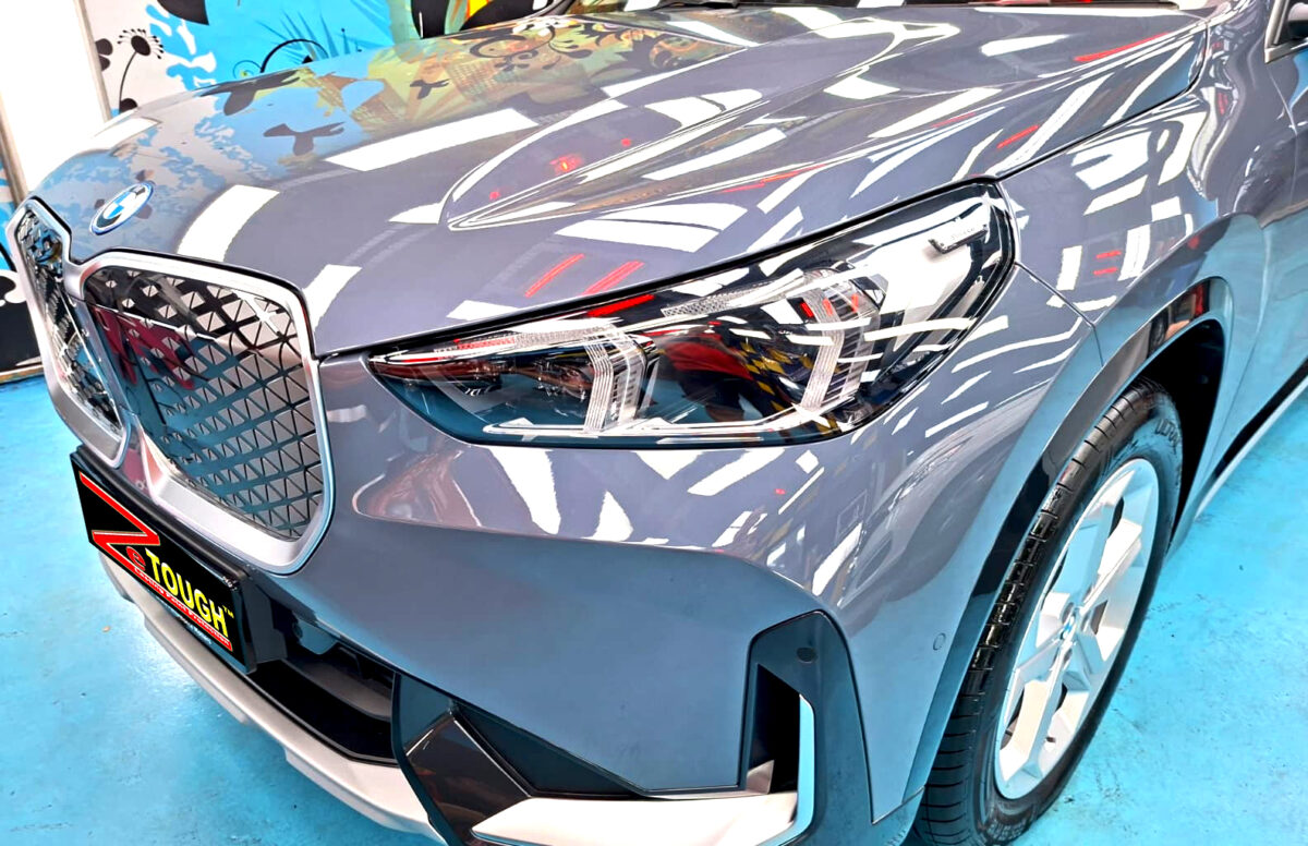 The BMW iX1's coated paintwork under workshop lighting.