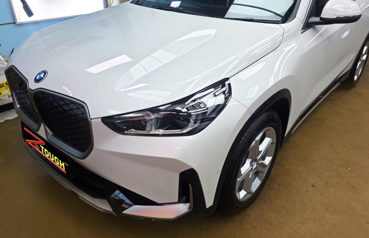 The BMW iX1's coated paintwork under workshop lighting.