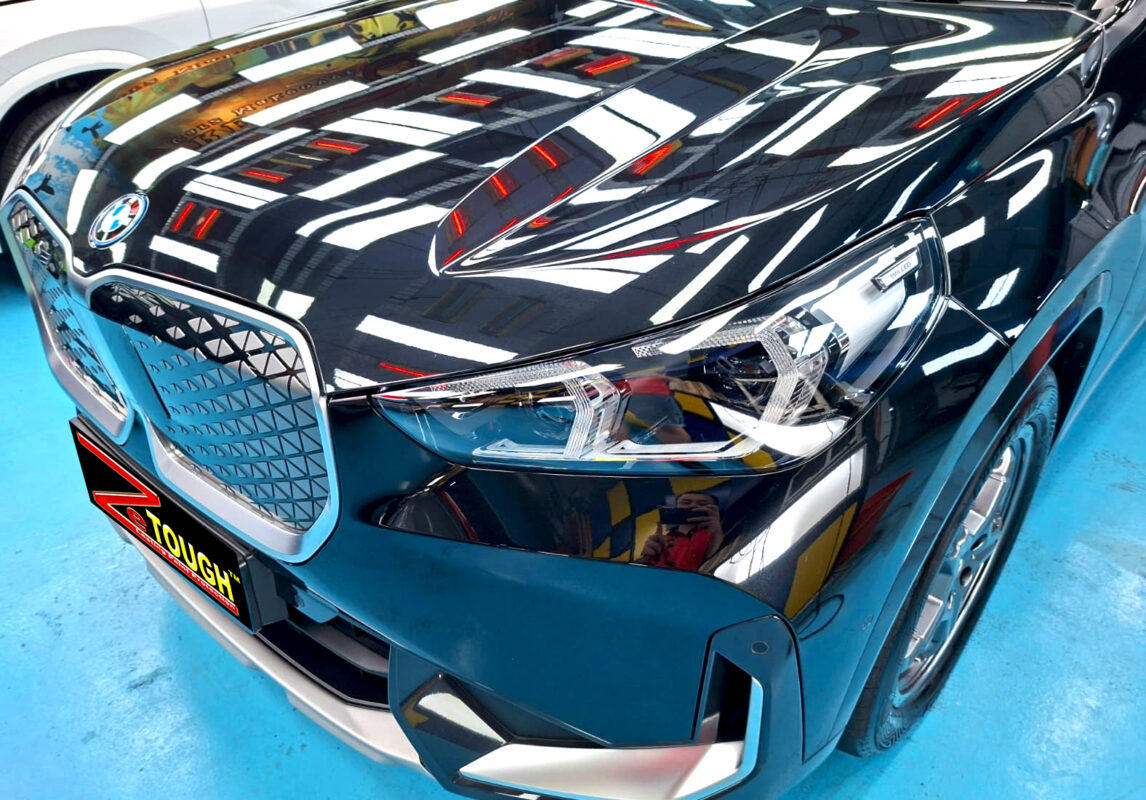 The BMW iX1's coated paintwork under workshop lighting.
