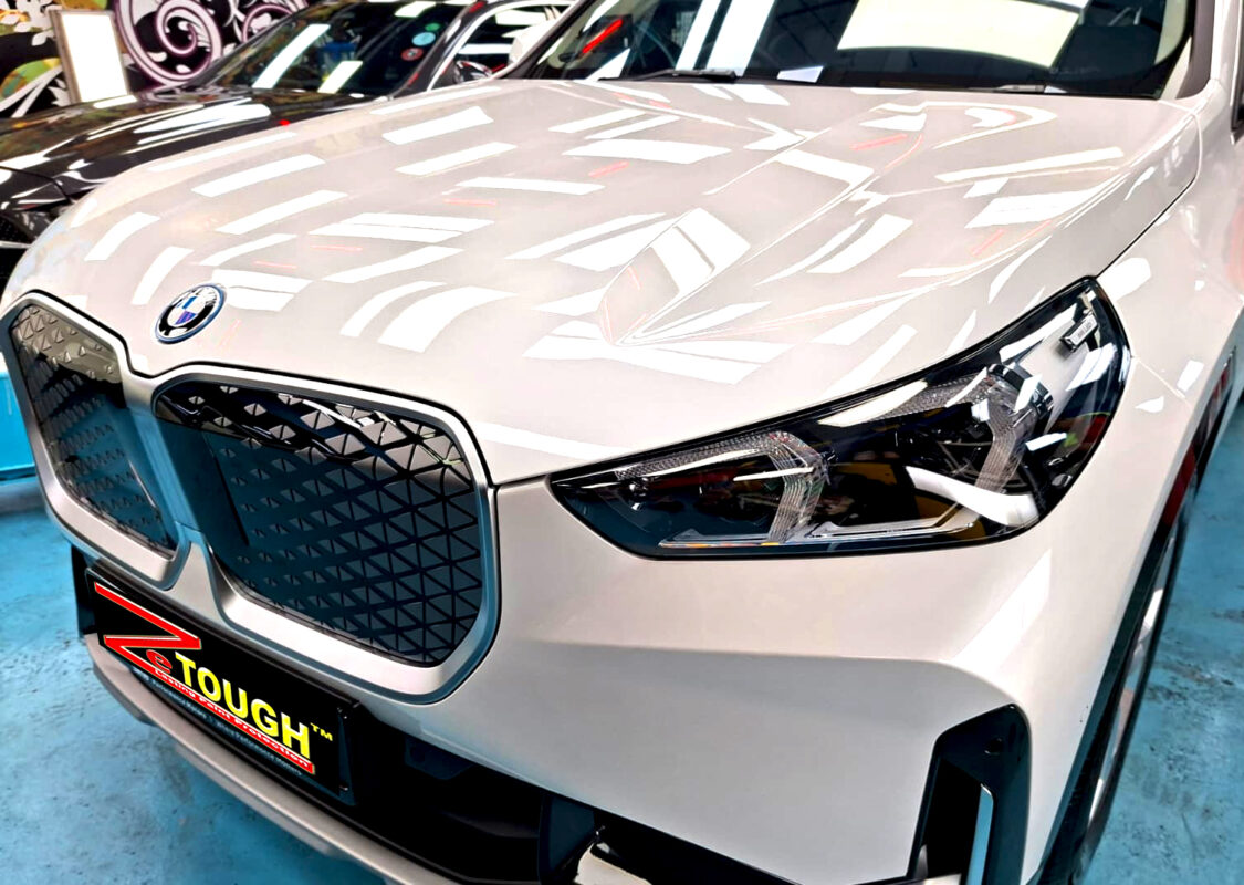 The BMW iX1's coated paintwork under workshop lighting.