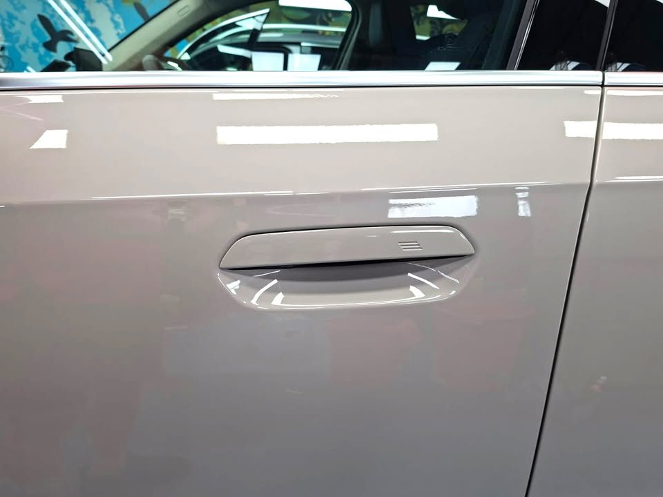 Door handle on the beige BMW iX1 with light reflected across the door panel.