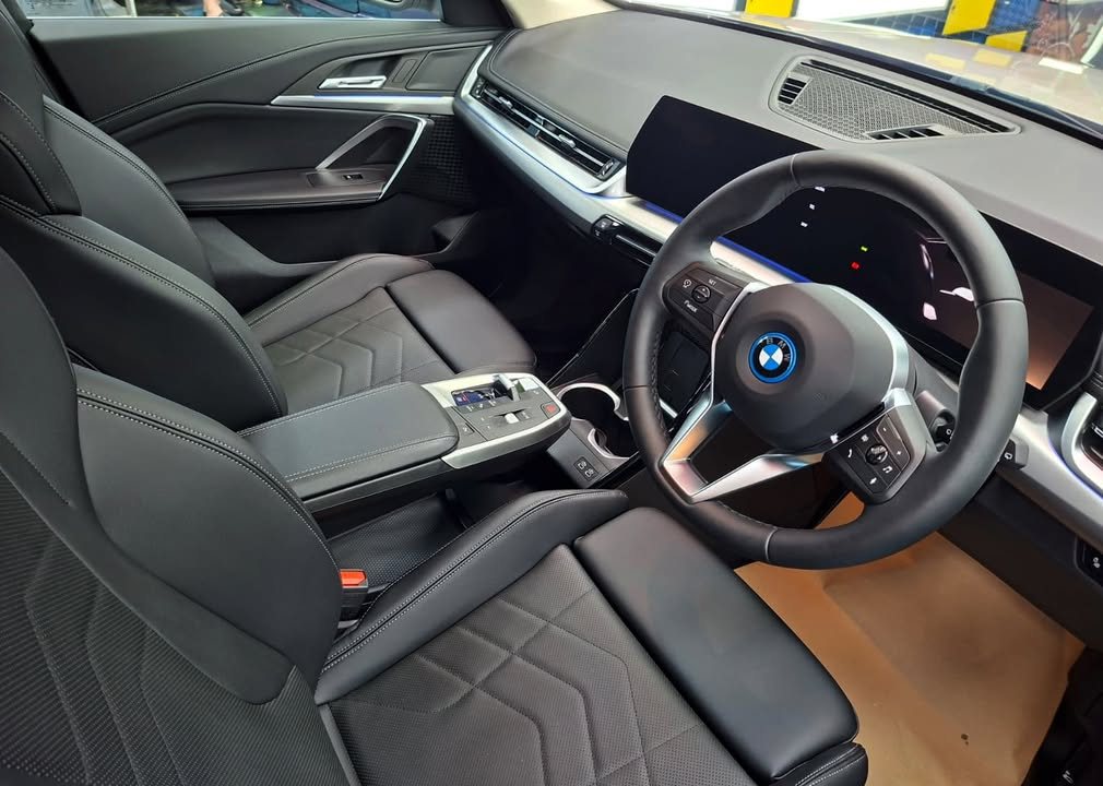 BMW iX1 cabin with black seats, steering wheel and curved display.