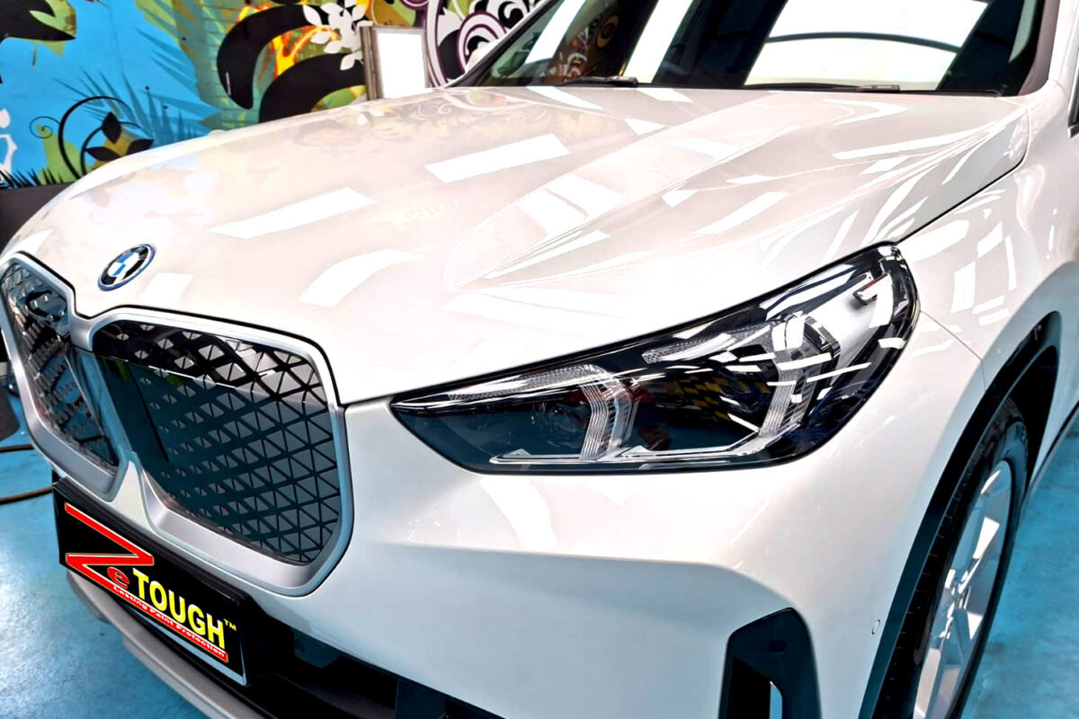 The BMW iX1's coated paintwork under workshop lighting.