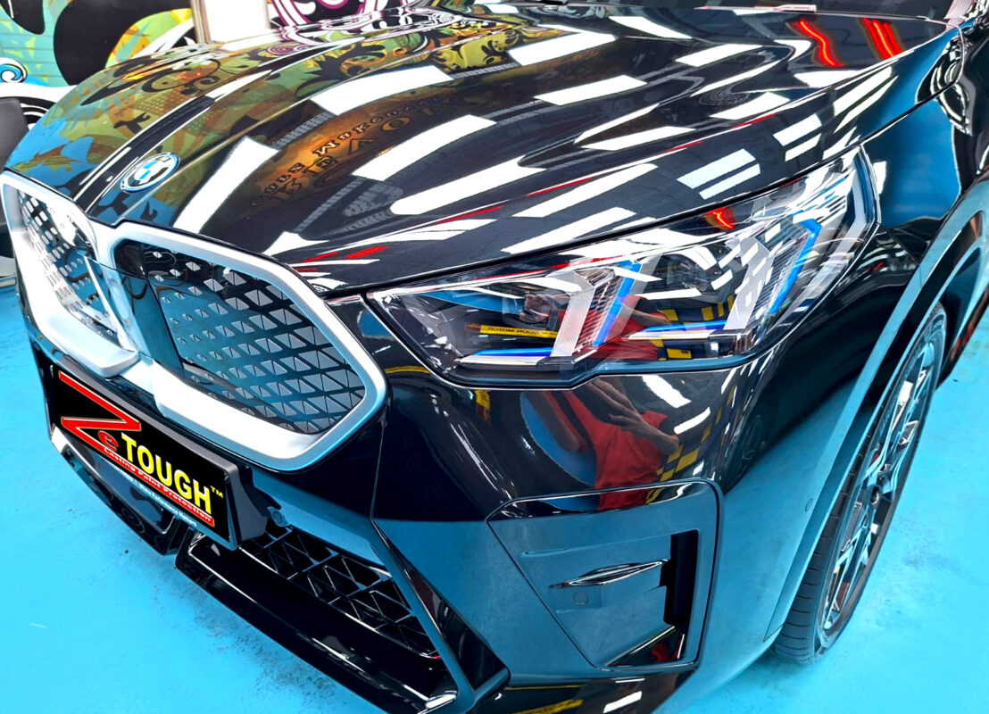 The BMW iX2's coated paintwork under workshop lighting.