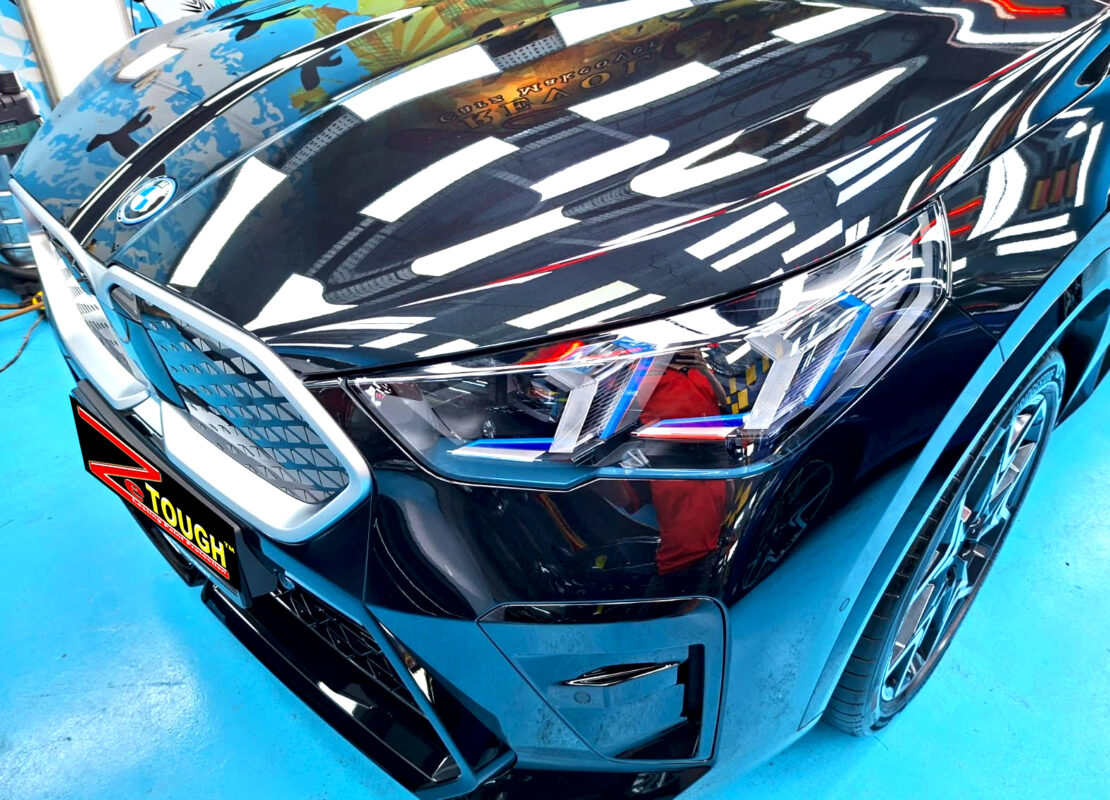 The BMW iX2's coated paintwork under workshop lighting.