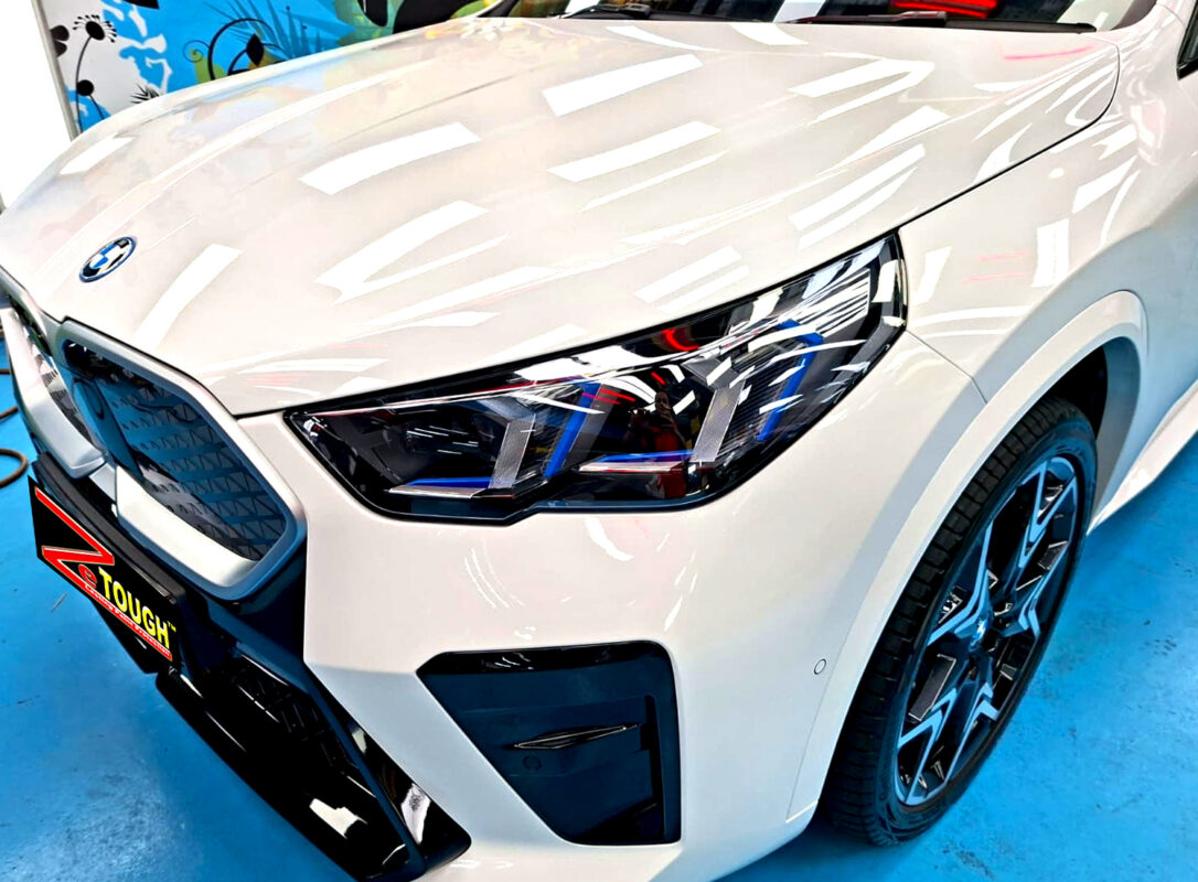 The BMW iX2's coated paintwork under workshop lighting.