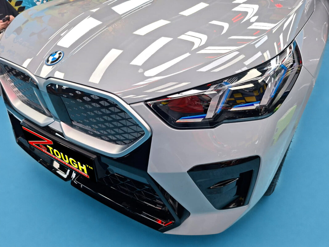The BMW iX2's coated paintwork under workshop lighting.