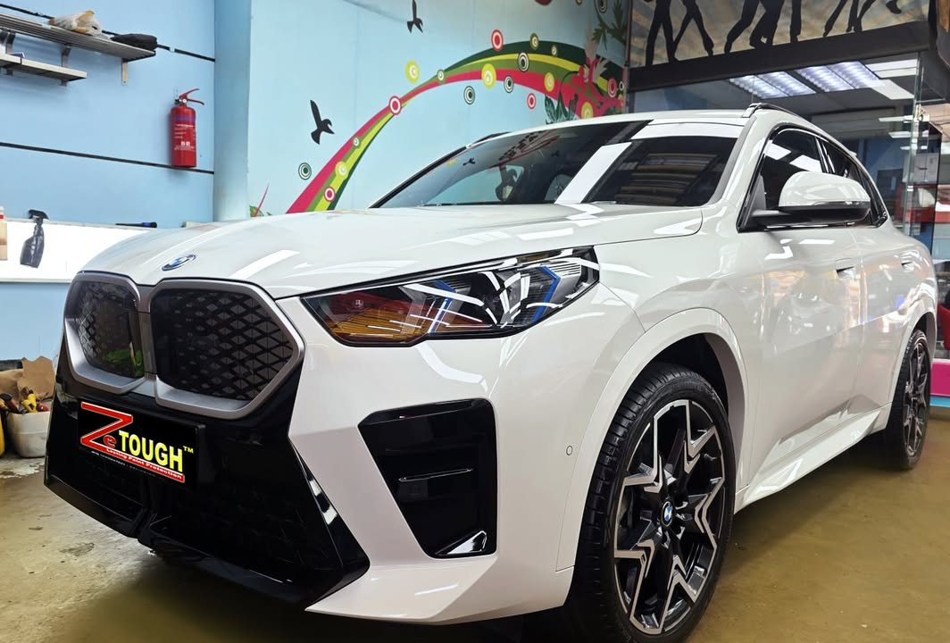 White BMW iX2, front view in the workshop with a ZeTough plate on the bumper.