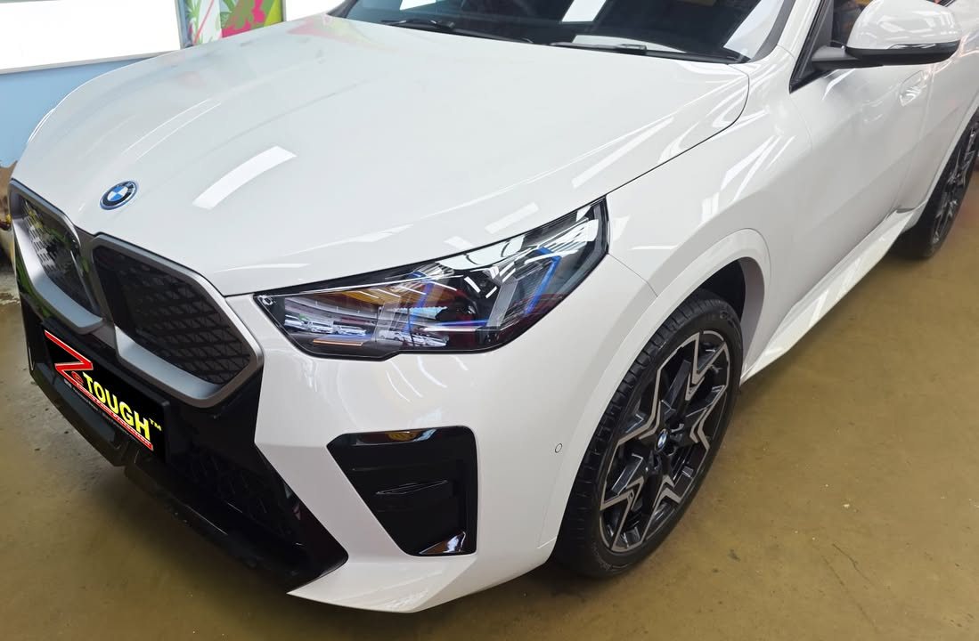 Front three-quarter view of the white BMW iX2 showing the kidney grille and headlamp.