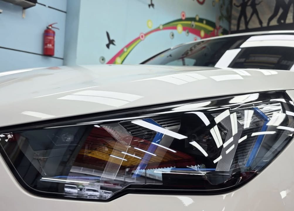 Close-up of the BMW iX2 headlamp and white bonnet edge.