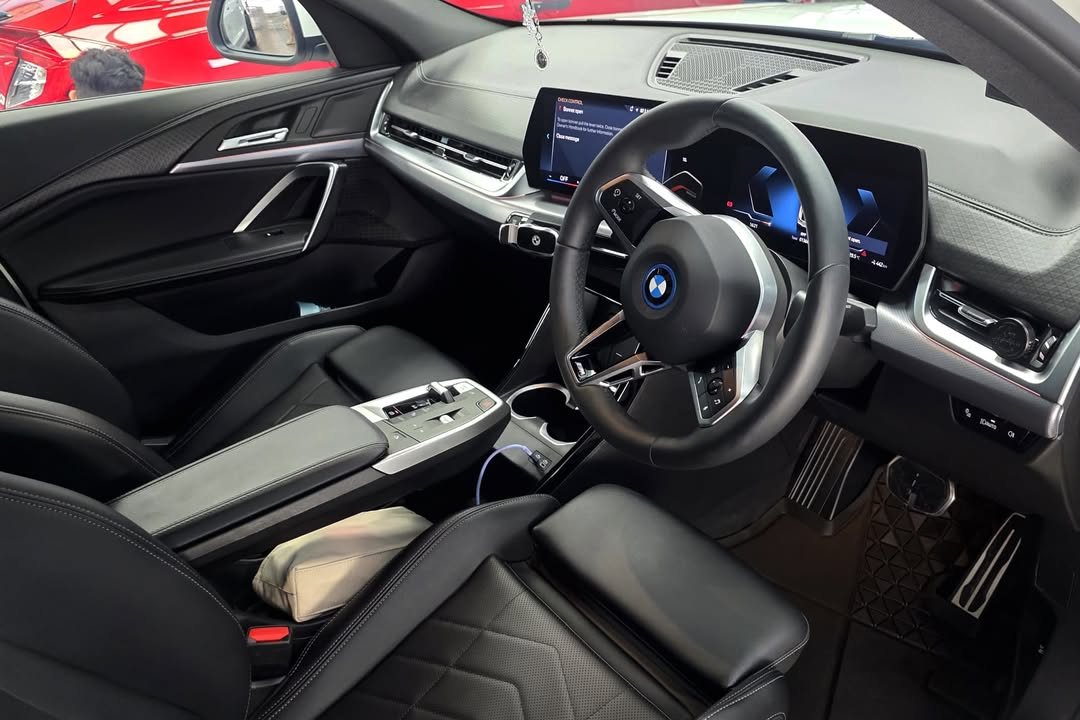 BMW iX2 cabin with black seats, steering wheel and curved display.