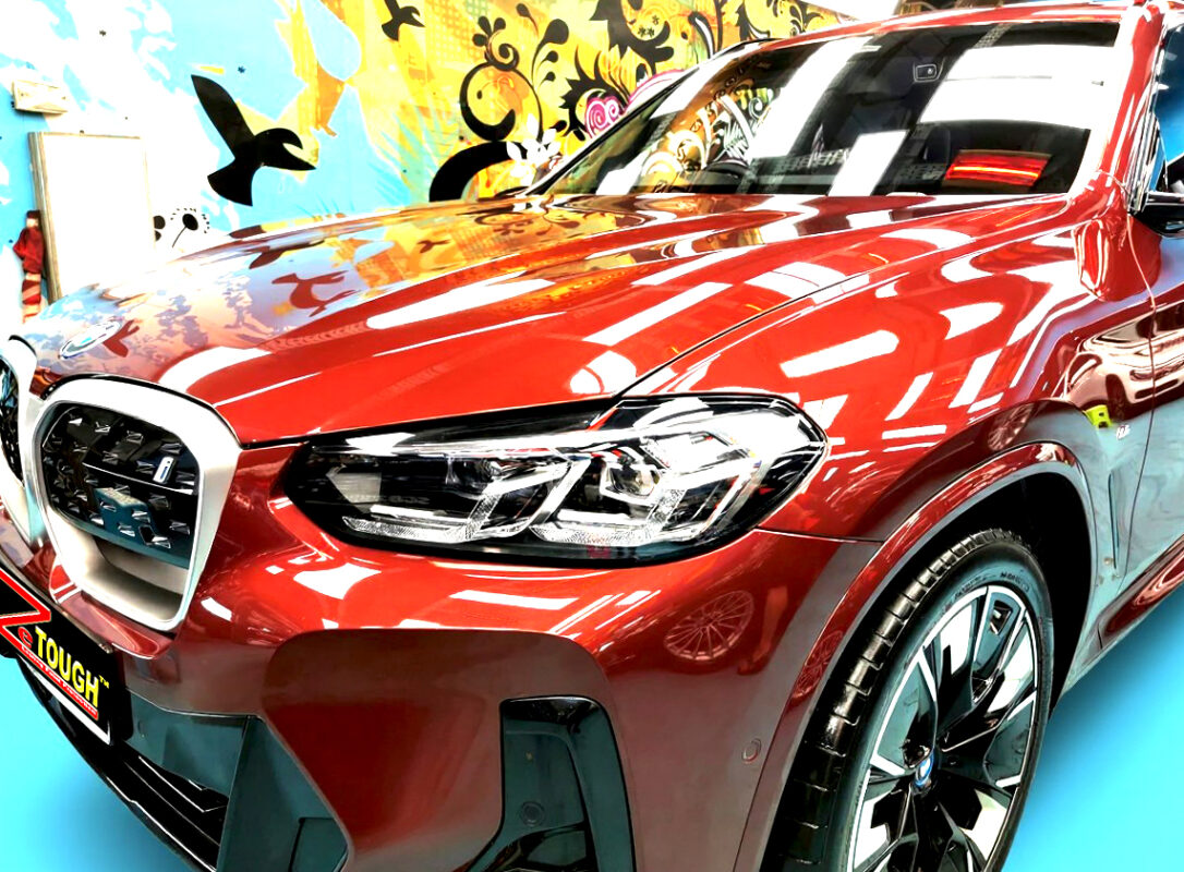 The BMW iX3's coated paintwork under workshop lighting.