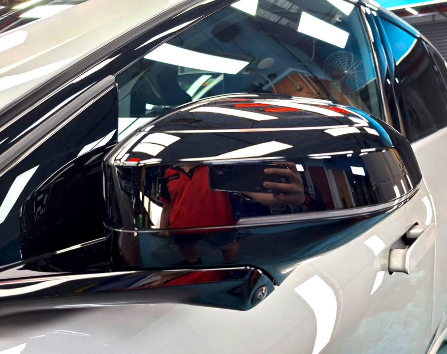 Gloss black side mirror cap reflecting the workshop.