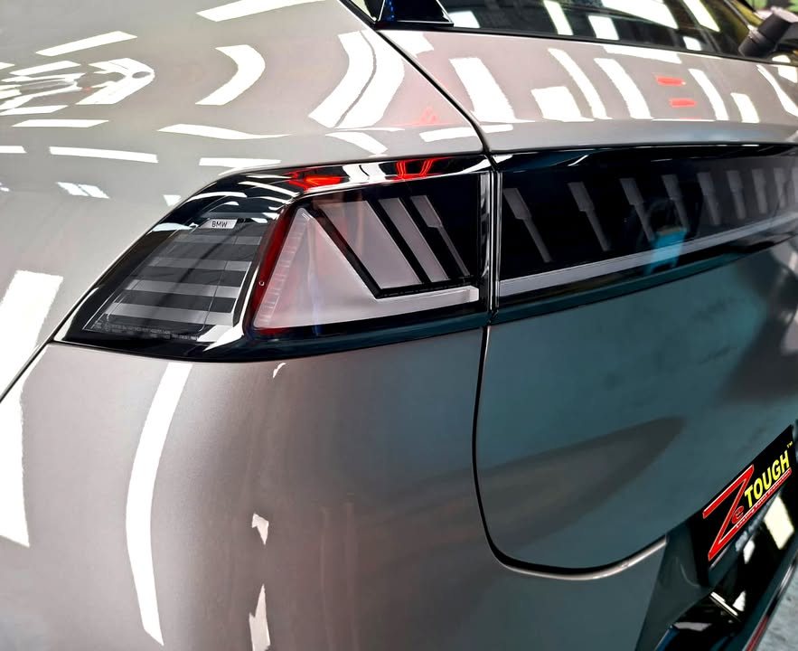 Close-up of the black tail light and rear quarter in grey paint.
