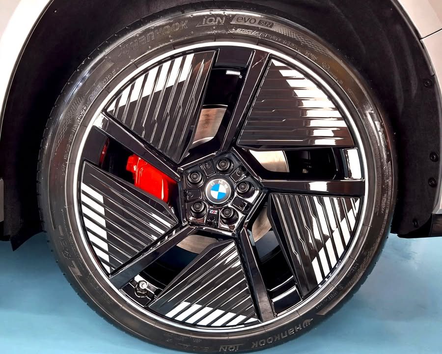 Black aero wheel with BMW centre cap and red brake caliper behind.