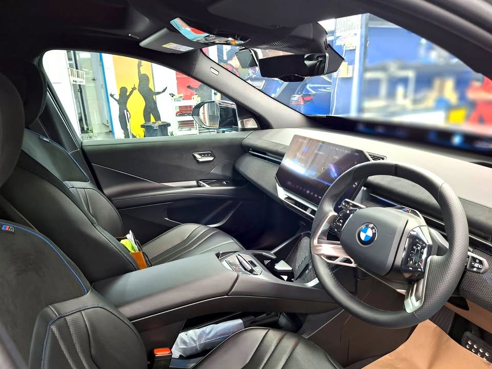 Cabin with black leather seats, steering wheel and curved dashboard screen.