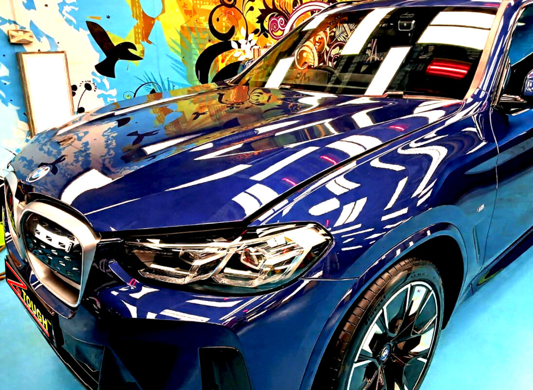 The BMW iX3's coated paintwork under workshop lighting.