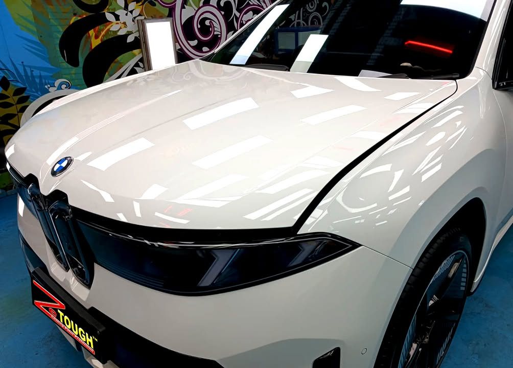 Front of the white iX3 showing the grille, lamps and gloss on the bonnet.