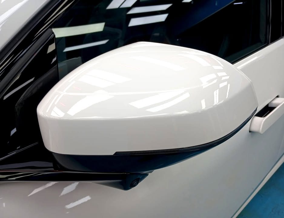 White wing mirror on the iX3 with ceiling lights reflected.