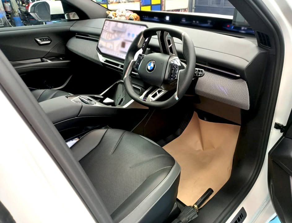 Front cabin of the iX3 with dark seats and a wide display across the dashboard.