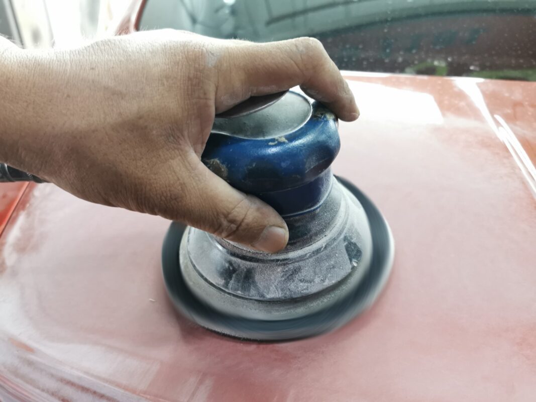 Machine-sanding a panel on the BMW M4 to take the surface back.