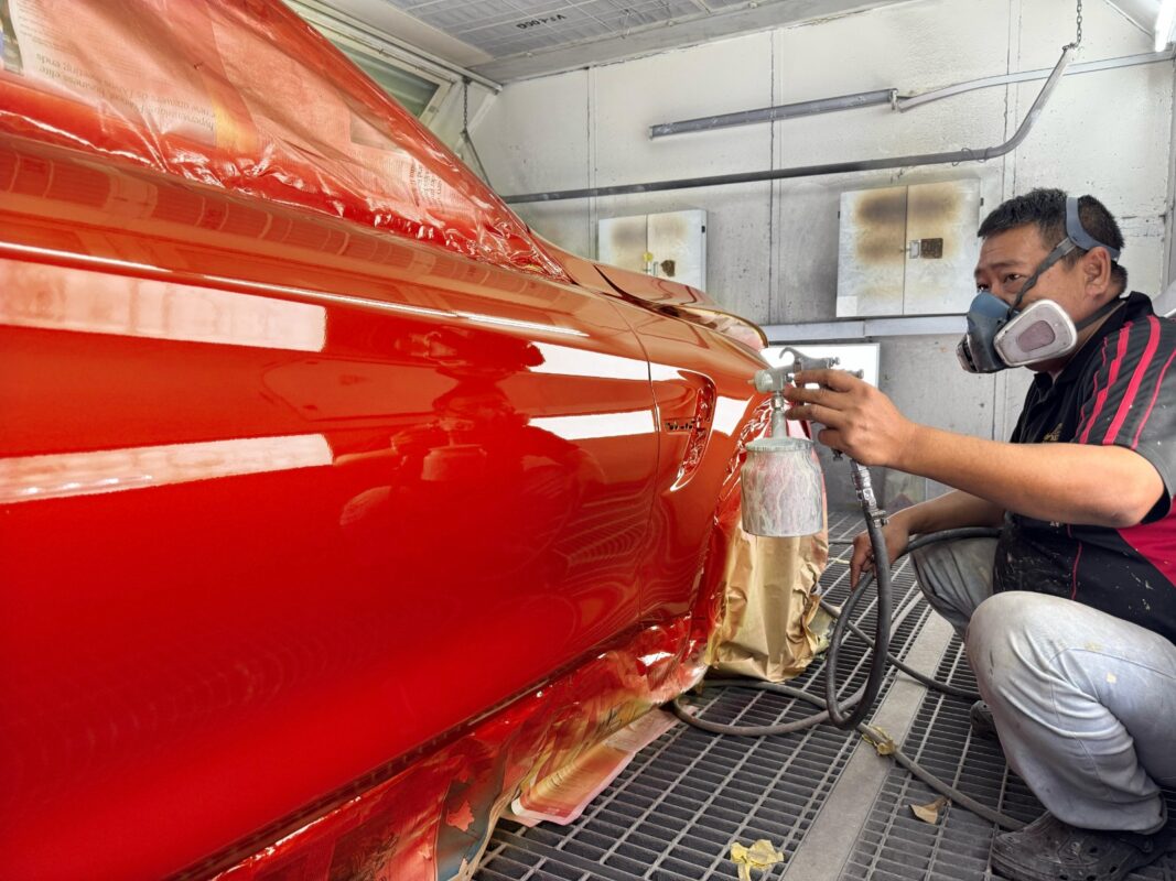 A Revol Carz painter laying the new coat onto the BMW M4 in the spray booth.