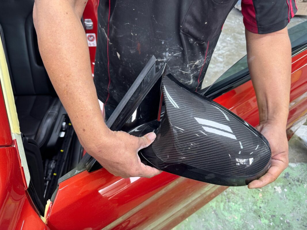 Refitting the BMW M4's carbon mirror cap after painting.