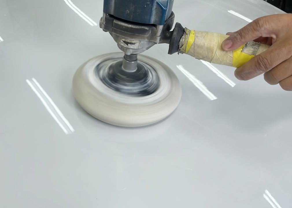 Rotary polisher with a wool pad on the glossy white paint.