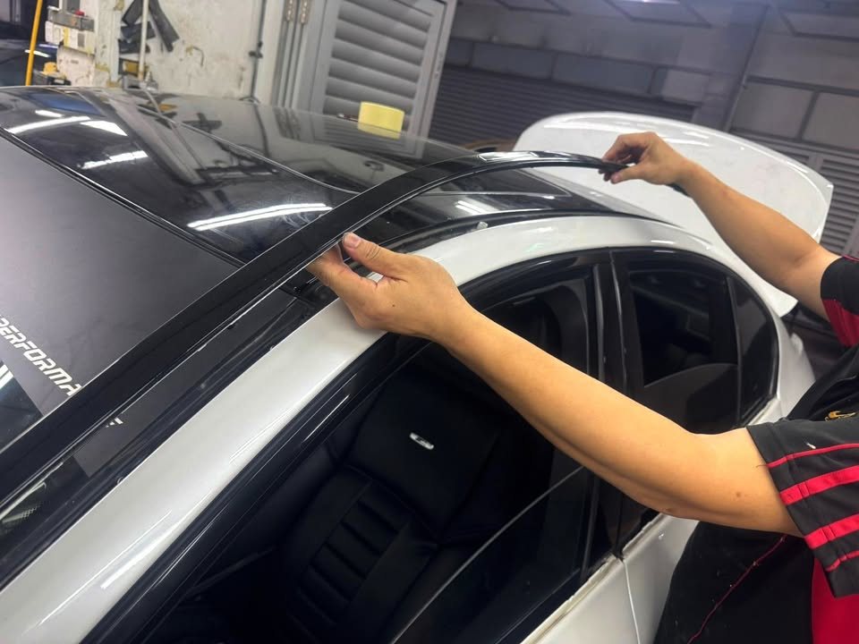 Technician refitting the roof trim strip on the M5.