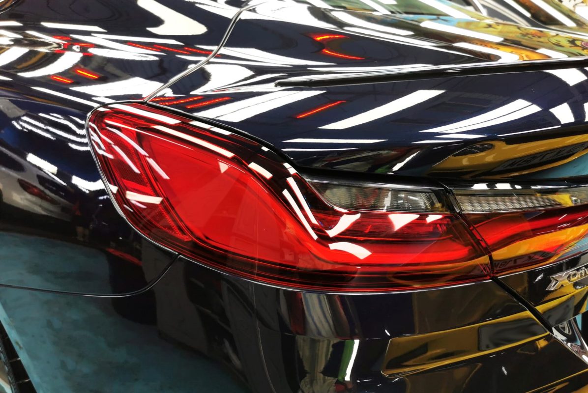 The coated bonnet of the BMW M850i under workshop lighting.