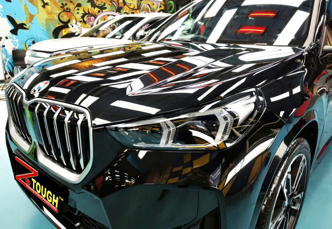 The BMW X1's coated paintwork under workshop lighting.