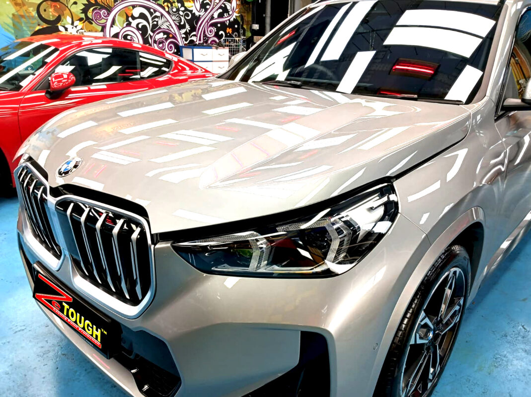 The BMW X1's coated paintwork under workshop lighting.