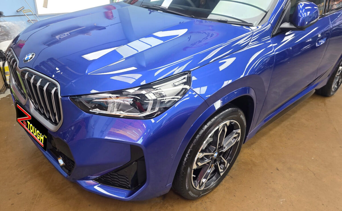 The BMW X1's coated paintwork under workshop lighting.