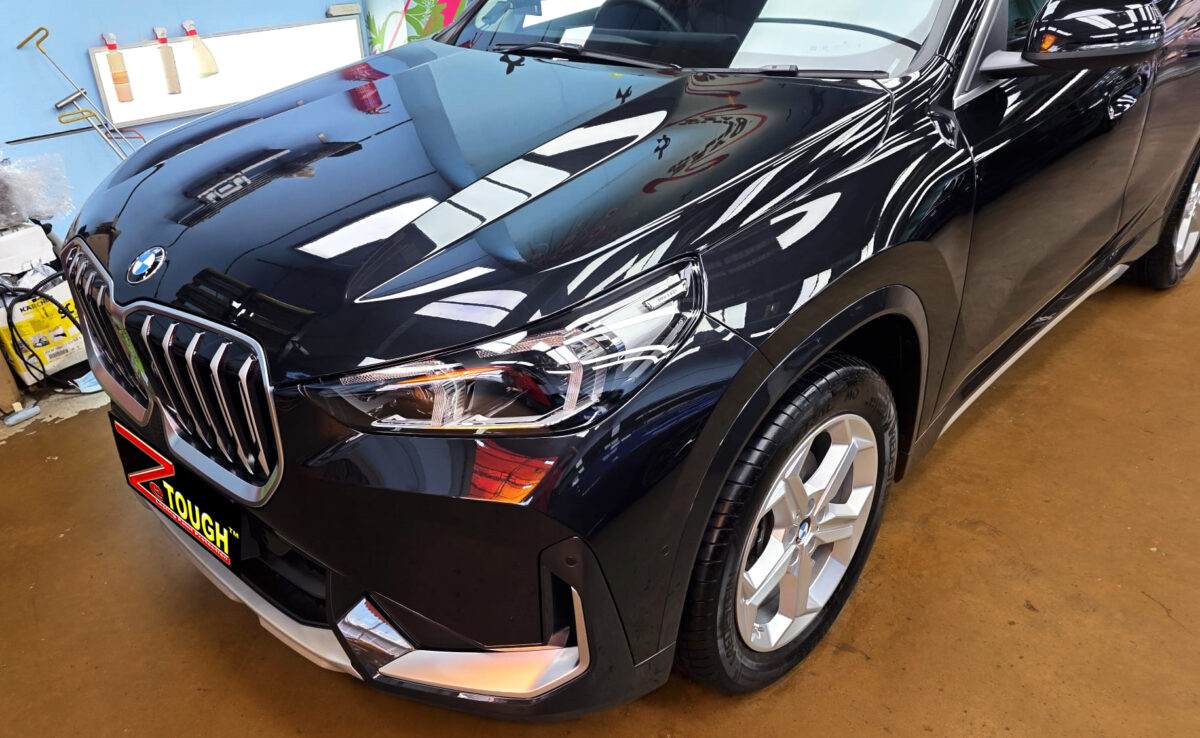 The BMW X1's coated paintwork under workshop lighting.