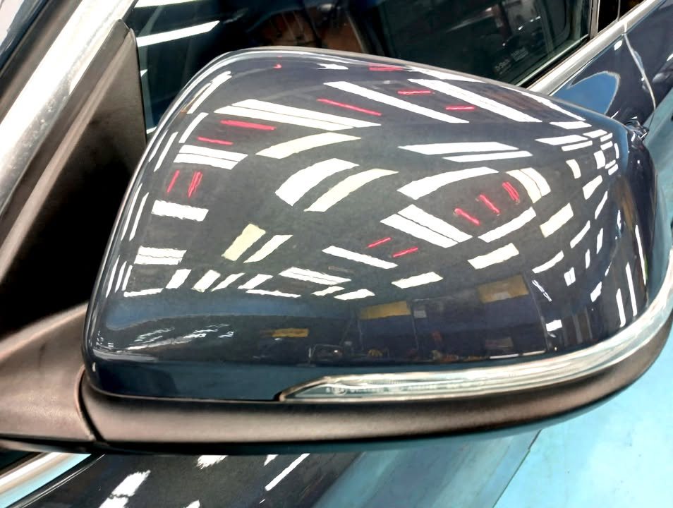 Blue side mirror cap of the X1 with sharp light reflections.