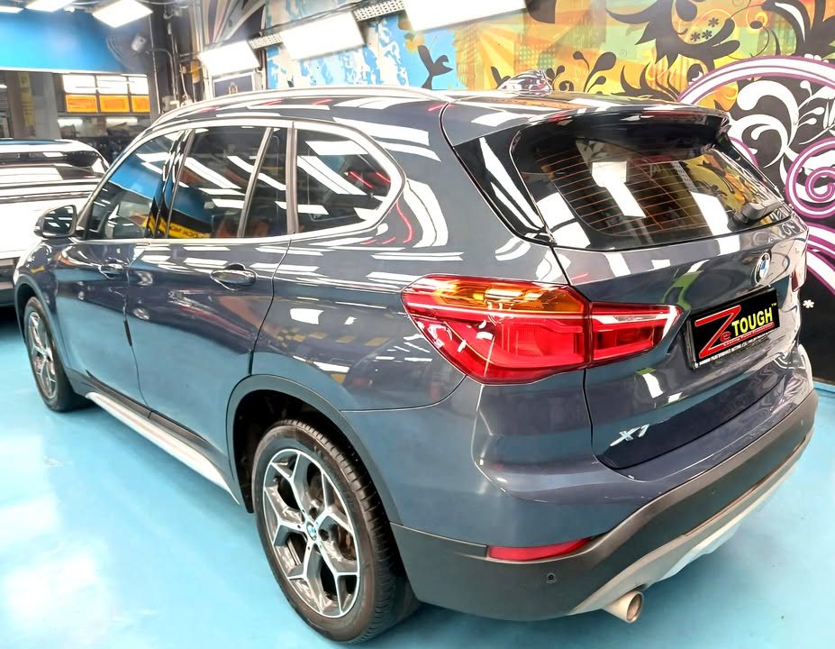 Rear three-quarter view of the blue BMW X1 showing the tail lights and X1 badge.