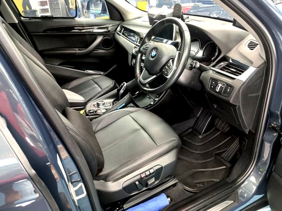Driver's side of the X1 cabin with black leather seats and steering wheel.